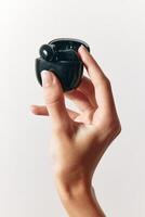 Hand holding small black earbud with thumb and finger touching top and bottom. close-up shot of photo