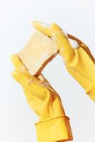 Person wearing yellow rubber gloves holding a soap and sponge on a white background. image ideal for photo