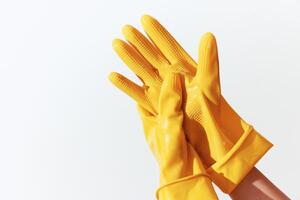 Pair of yellow rubber gloves held by a woman's hands on a white background with space for text photo