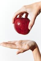 Person holding a red apple with one hand and touching it with the other hand. photo