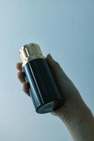 Hand holding elegant black and gold perfume bottle on blue background with space for text in top photo