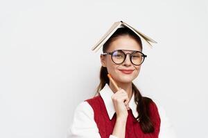 student, thinking, creativity, playful pose with a book on her head, wearing glasses and a sweater photo