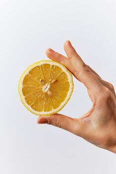 Hand holding half of a lemon on a white background with empty space in the middle. photo