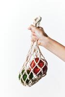 Knitted bag with apples in person's hand, green apple, on white background with copy space. photo