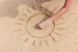 Sun drawing of a person on a beach, creating a circle in the sand with the sun in the center. photo