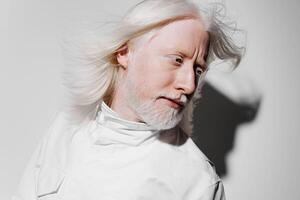 A striking image of a man with long white hair and a beard, dressed in white, set against a photo
