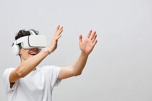 A joyful young man wearing a VR headset interacts with a virtual environment, waving his hands in photo