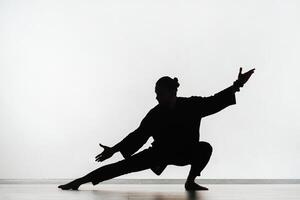 Silhouette of a person practicing qigong energy exercises on a light background photo