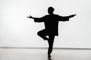 Silhouette of a person practicing qigong energy exercises on a light background photo