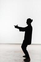 Silhouette of a person practicing qigong energy exercises on a light background photo