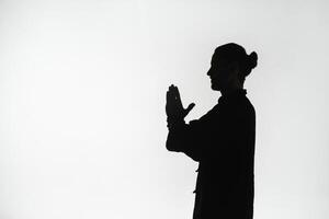 Silhouette of a person practicing qigong energy exercises on a light background photo