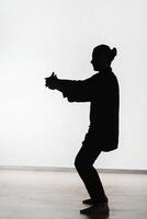 Silhouette of a person practicing qigong energy exercises on a light background photo