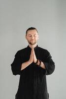 A man in black kimano practicing qigong energy exercises indoors photo