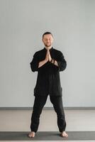 A man in black kimano practicing qigong energy exercises indoors photo