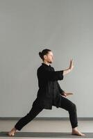 A man in black kimano practicing qigong energy exercises indoors photo