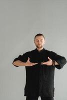 A man in black kimano practicing qigong energy exercises indoors photo