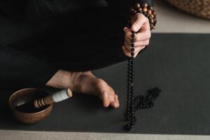 close-up of a man in a black kimono sitting in a lotus position on a gym mat in the interior photo