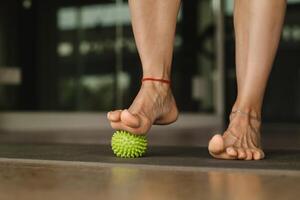 Close - up of the legs of a woman performing gymnastic exercises to correct flat feet during ball massage at home photo