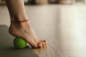 Close - up of the legs of a woman performing gymnastic exercises to correct flat feet during ball massage at home photo