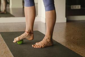 Close - up of the legs of a woman performing gymnastic exercises to correct flat feet during ball massage at home photo
