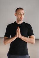 An athletically built man does yoga in the gym on a mat photo