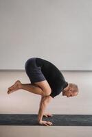 An athletically built man does yoga in the gym on a mat photo