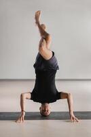 A man performs a yoga pose with support on his head in the gym. Yogi in a headstand photo