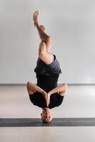 A man performs a yoga pose with support on his head in the gym. Yogi in a headstand photo