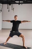 An athletically built man does yoga in the gym on a mat photo