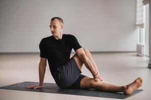 An athletically built man does yoga in the gym on a mat photo