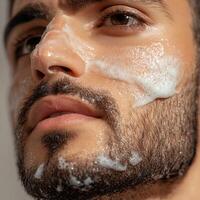Close-up of a man applying a facial cleanser with a foamy texture on his beard. photo