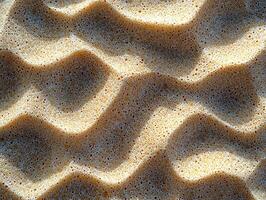 Textured close-up of sand surface, showcasing natural patterns and grain in sunlight. photo