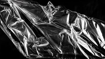 Shiny plastic sheet crumpled on a dark background, creating an abstract texture and pattern. photo