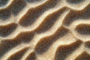 Textured sandy surface with subtle waves and shadows, natural light highlighting grains. photo