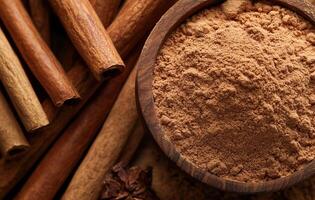 Cinnamon sticks and ground cinnamon in a wooden bowl on a dark background. photo