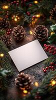 Blank card surrounded by pine cones and festive decorations on a dark background. photo