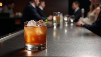 A cocktail glass filled with an alcoholic beverage sits on a bar table at a nightclub or restaurant photo