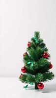White background adorned with green confetti and red ornaments around a miniature Christmas tree photo