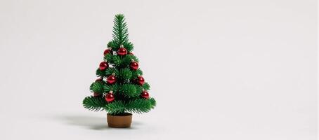 White background adorned with green confetti and red ornaments around a miniature Christmas tree photo