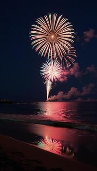 Fireworks light up the tranquil beach at night casting vibrant reflections on the calm ocean and shoreside photo