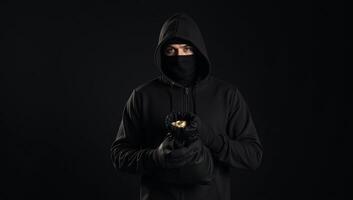 A shadowy bank robber stands against a dark backdrop clutching a bag of stolen cash outlined by a hint of a closed bank door photo