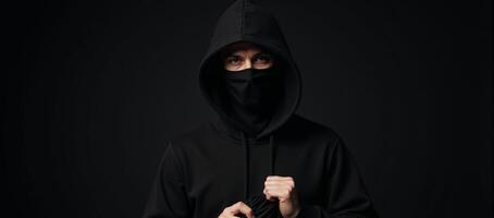 A shadowy bank robber stands against a dark backdrop clutching a bag of stolen cash outlined by a hint of a closed bank door photo