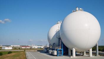 A modern petrochemical factory features spherical BPVC gas tanks in a setting with clear blue skies and other storage tanks for cryogenic liquids under the gaze of a processing station photo