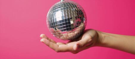Hand with glittery disco ball against vibrant pink backdrop Fun Retro Party Theme photo