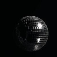 A rotating blackandwhite disco ball glows against dark background amidst flashes of light and dramatic shadows photo
