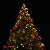 Festive Christmas tree with red black garland lit by warm glow 8k 3D render photo