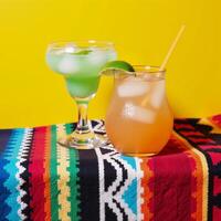 A colorful Mexicaninspired tableau showcases two margaritas against a sunny yellow backdrop photo