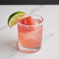 A cooling watermelonlaced tequila cocktail served over ice and garnished with a slice of lime photo