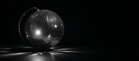 A rotating blackandwhite disco ball glows against dark background amidst flashes of light and dramatic shadows photo