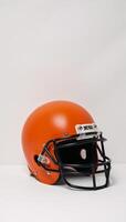Bright orange American football helmet with black face guard highlighted against clean white backdrop photo